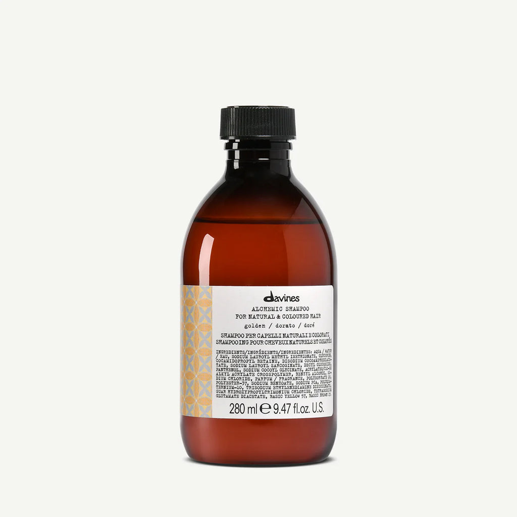 Flaska med Alchemic Shampoo Golden, ett schampo i en brun transparent flaska med svart skruvkork och etikett med text och mönster, perfekt för hårvård.