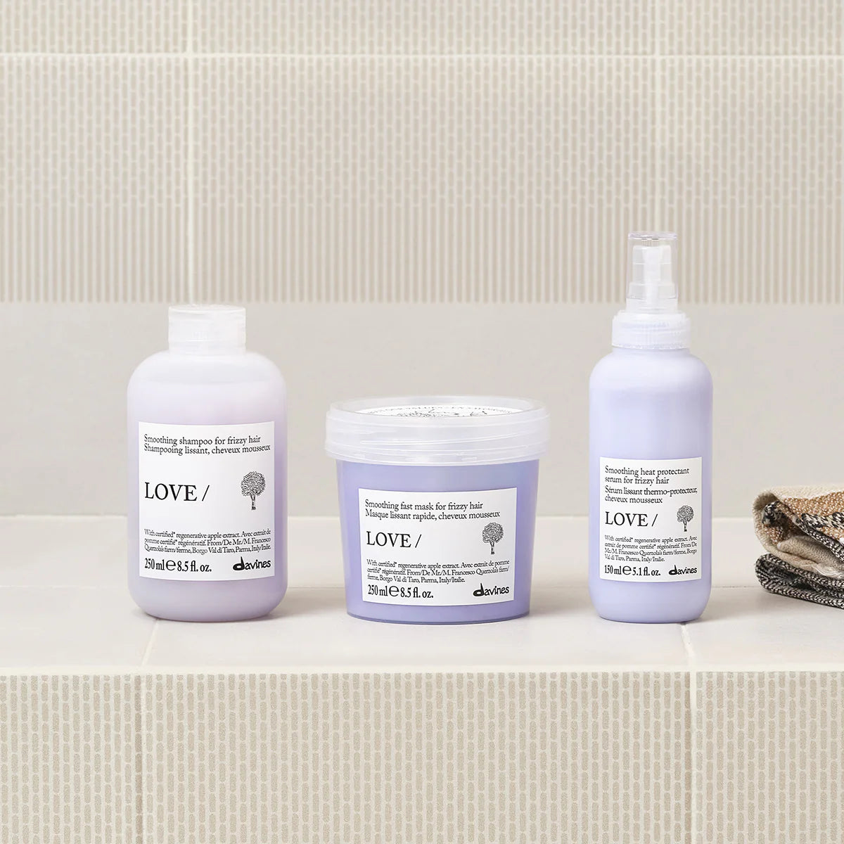 Love Smoothing Heat Protectant Serum i ljuslila förpackning tillsammans med matchande hårinpackning och schampo från Davines i miljövänliga hårvårdsprodukter.