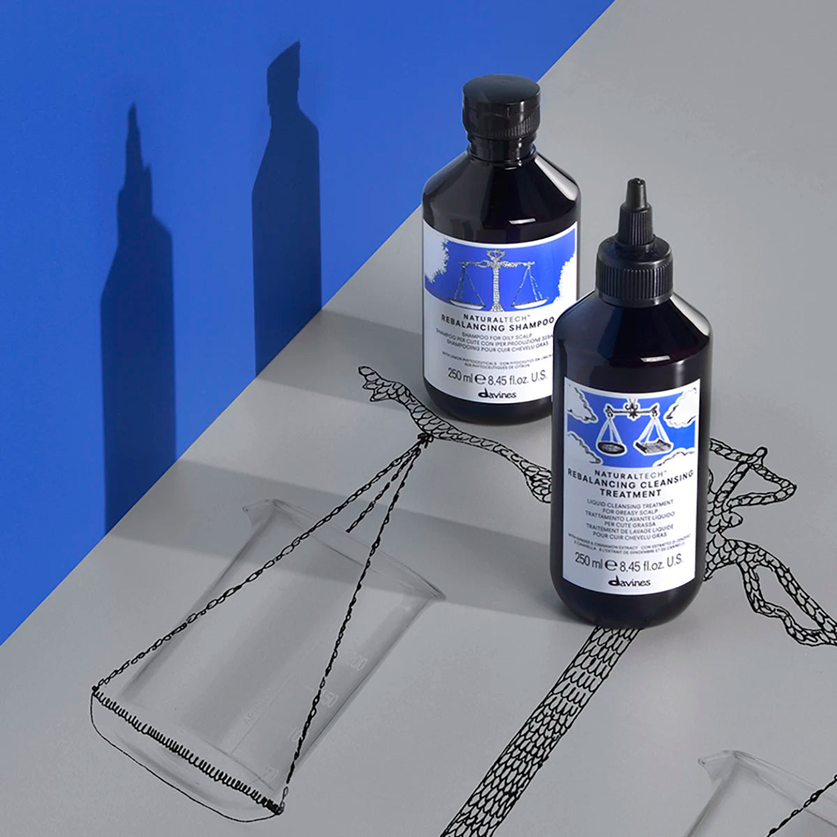 Naturaltech Rebalancing Cleansing Treatment-flaska med blå etikett och svart lock ståendes på grå yta med en illustration av en våg, bredvid en annan flaska från samma serie.