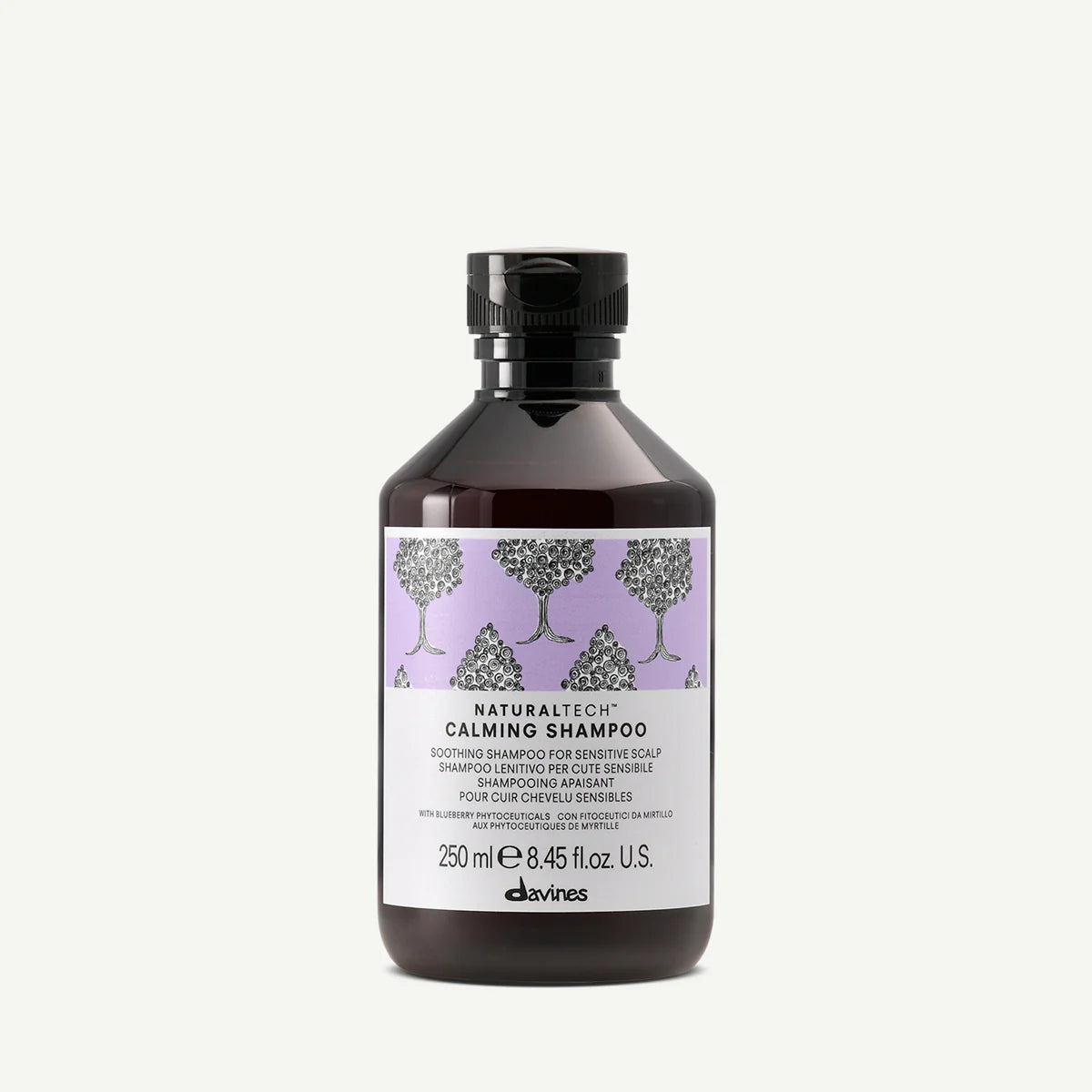Flaska med Naturaltech Calming Shampoo, ett milt schampo för känslig hårbotten med lugnande egenskaper och en diskret lila etikett med trädillustrationer.