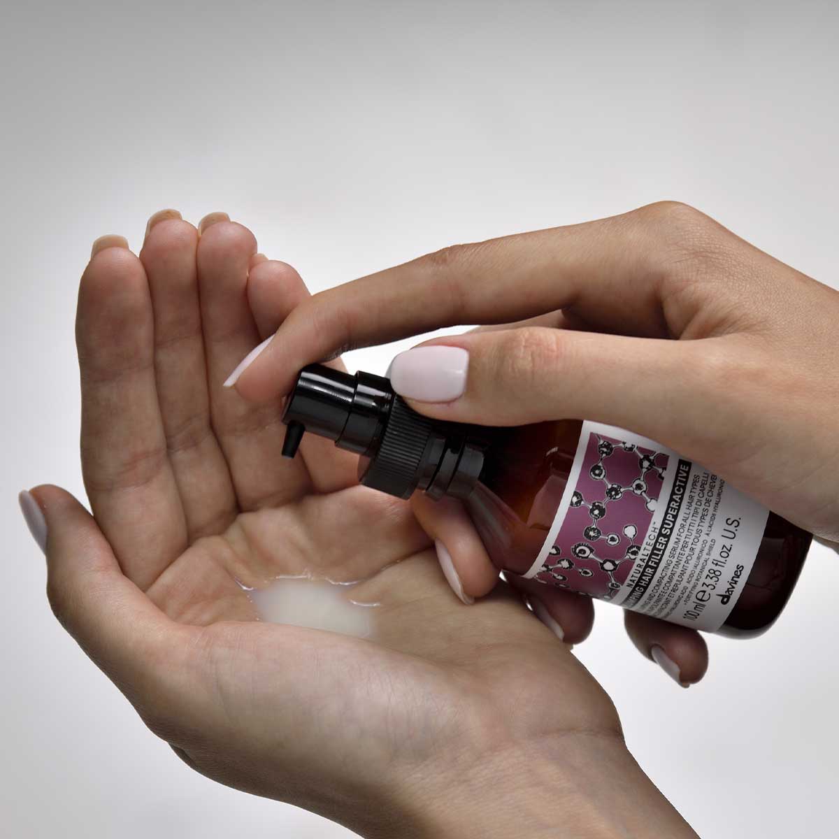 En person som pumpar ut Naturaltech Replumping Hair Filler i handen, en mjölkvit hårbehandling för volym och vård i ett miljövänligt hårvårdssortiment.