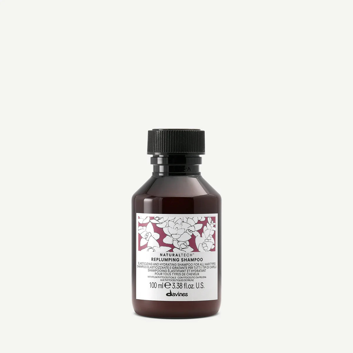 Naturaltech Replumping Shampoo i en mörk flaska med etikett som visar blommönster, ett miljövänligt schampo för återfuktning och volym.