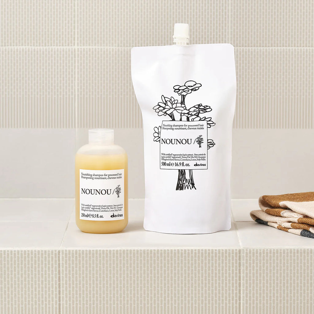 Nounou Nourishing Shampoo i två miljövänliga förpackningar på badrumshylla, schampo för vårdande och närande hårvård från Davines.