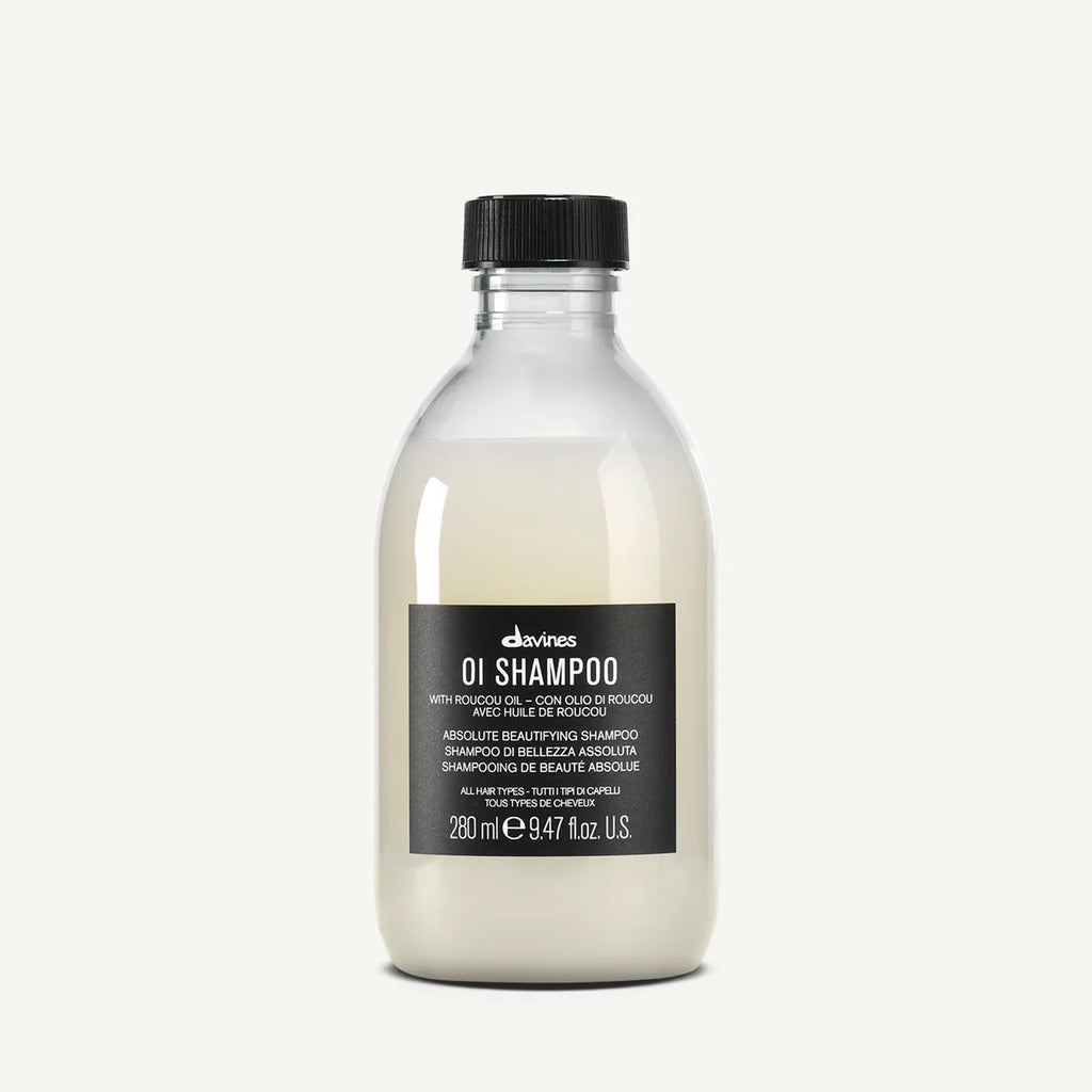 Flaska med OI/Shampoo från Davines, en mjölkvit schampo för alla hårtyper med svart etikett och svart lock.
