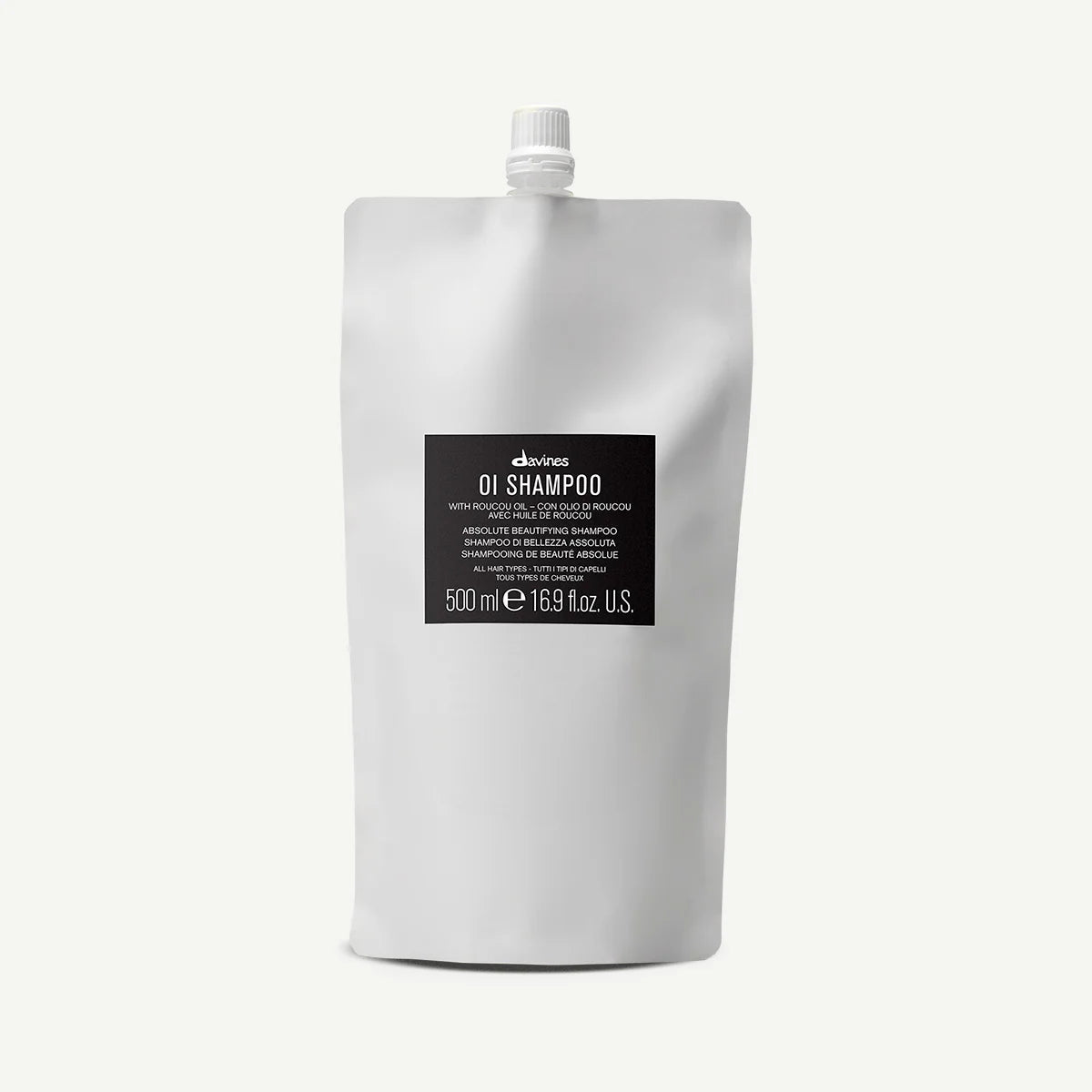 Vit påse med svart etikett innehållande 500 ml OI/Shampoo från Davines, ett miljövänligt schampo lämpat för alla hårtyper.
