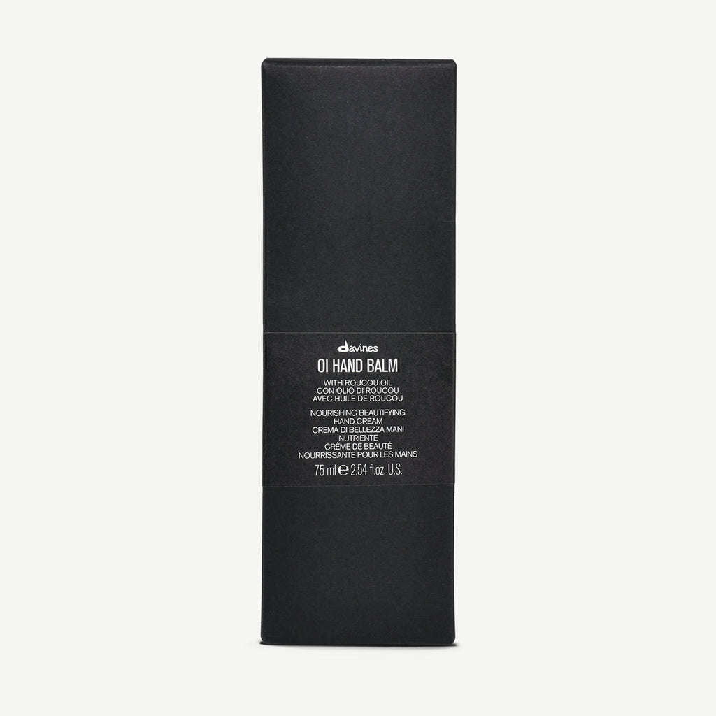 Svart förpackning för OI/Hand Balm med minimalistisk design och text som beskriver produkten som närande handkräm med Roucou-olja.