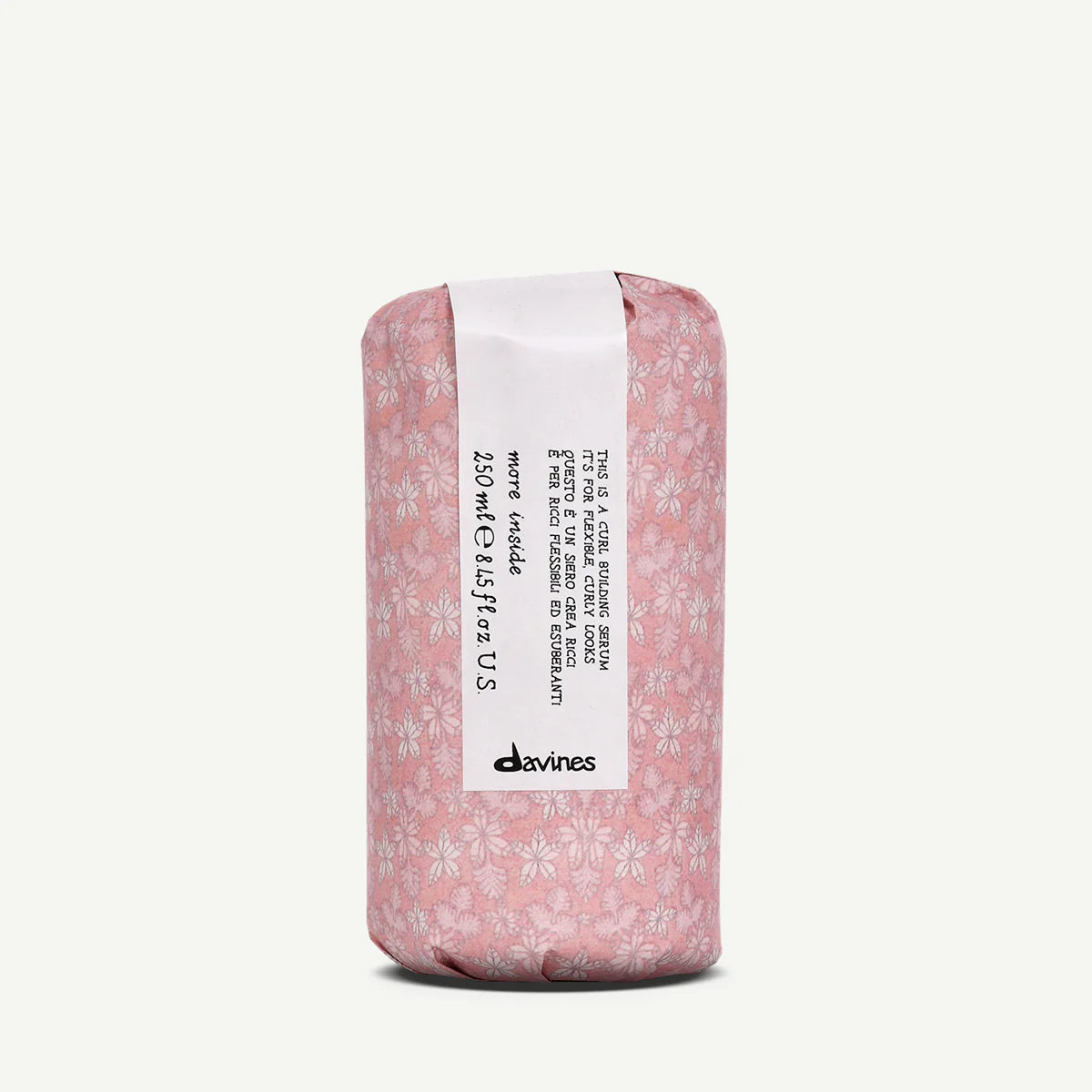 This is a Curl Building Serum i rosa förpackning med blommönster, en stylingprodukt från Davines som hjälper till att definiera och vårda lockigt hår.