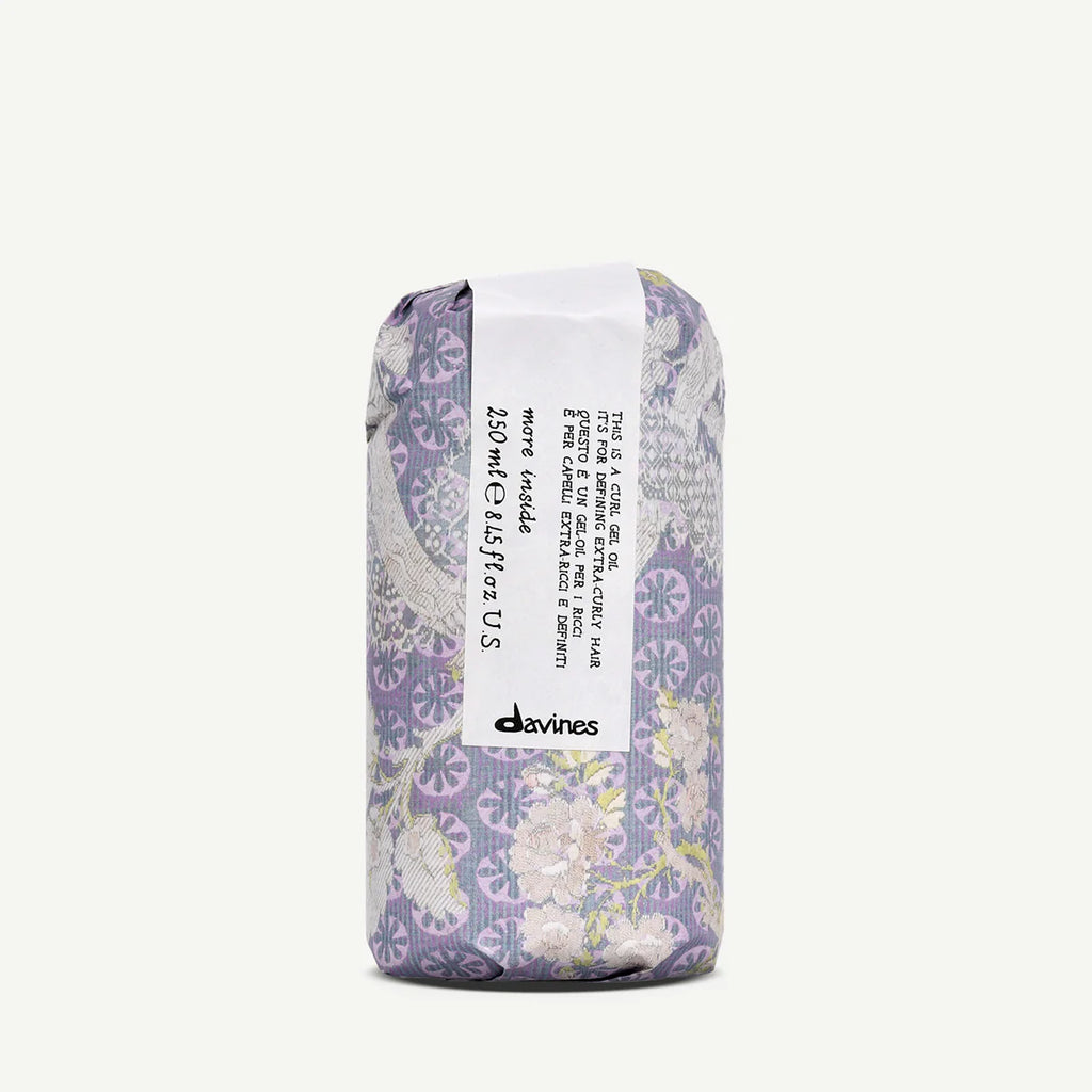 Förpackning av This is a Curl Gel Oil från Davines, designad med blommönster i lila och beige nyanser, för styling av lockigt hår med vårdande olja.