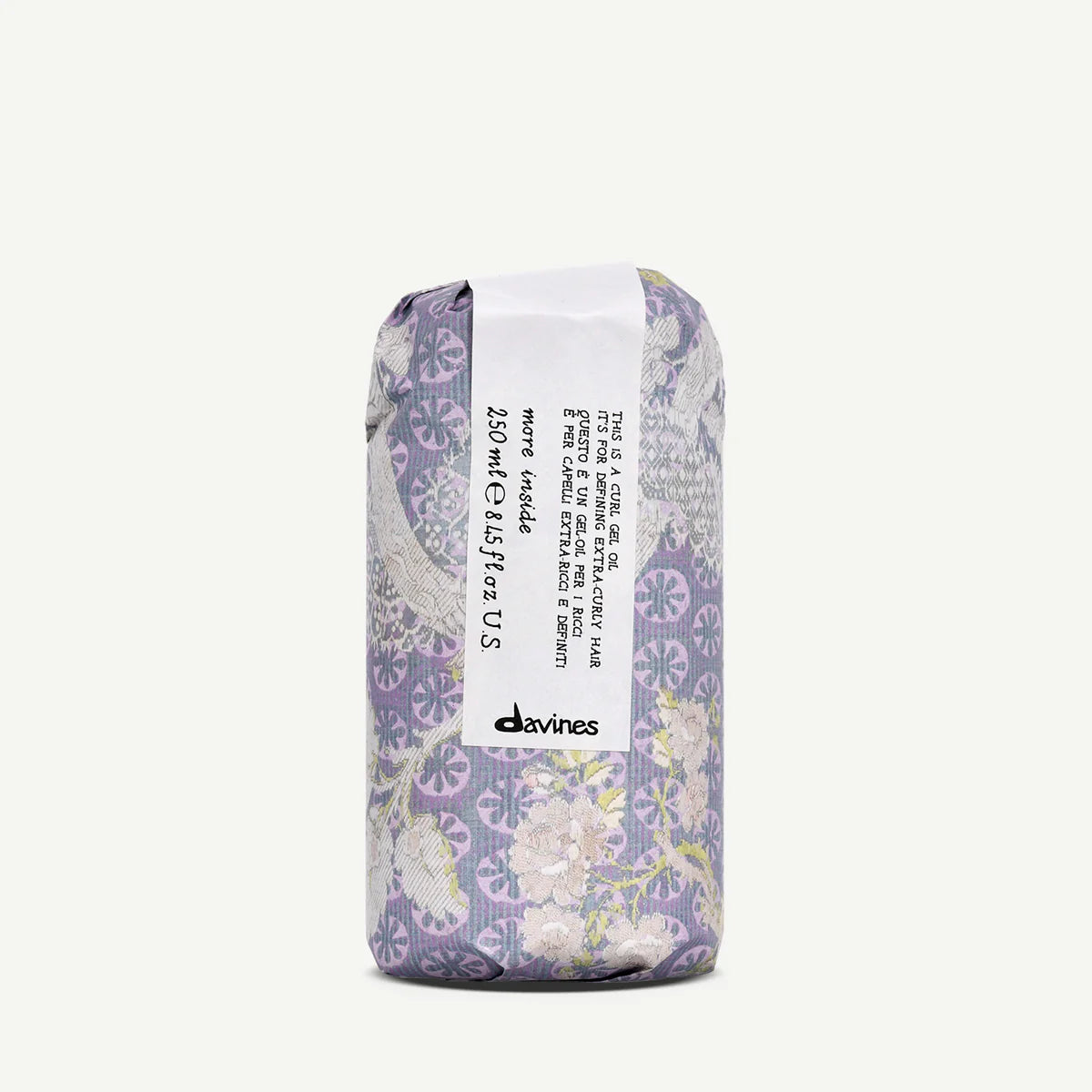 Förpackning av This is a Curl Gel Oil från Davines, designad med blommönster i lila och beige nyanser, för styling av lockigt hår med vårdande olja.