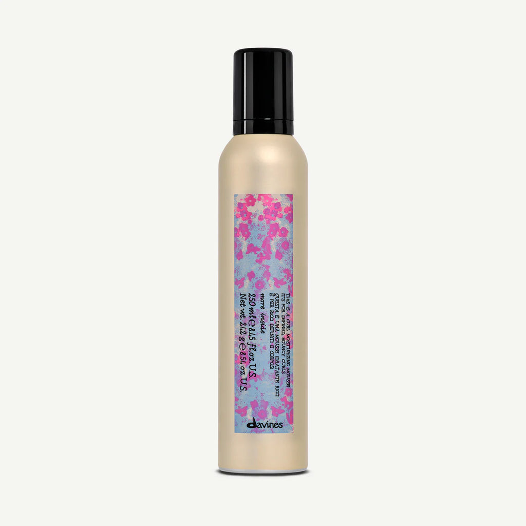 This is a Curl Moisturizing Mousse i en beige flaska med svart lock och färgglad etikett, en stylingprodukt för lockigt hår med återfuktande egenskaper.