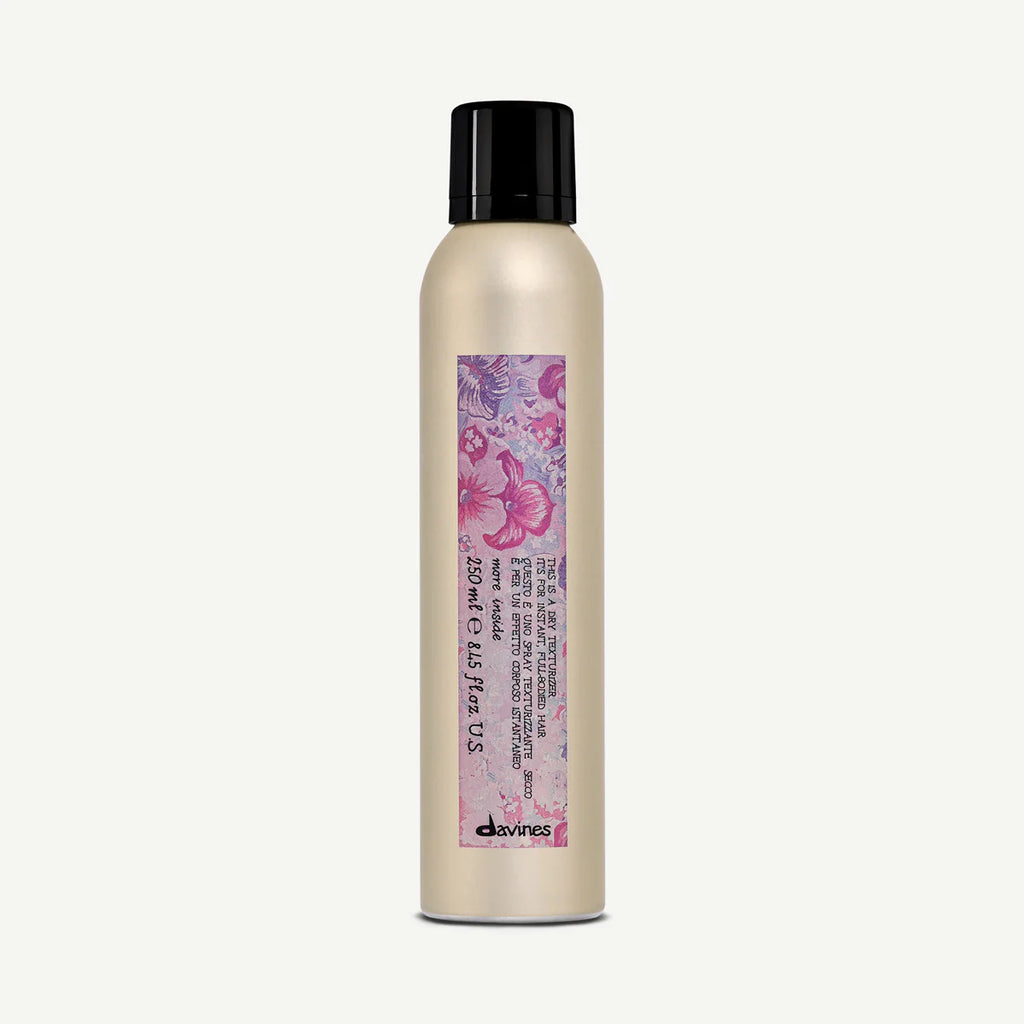 This is a Dry Texturizer i en elegant, beige sprayflaska med svart lock och färgglatt mönster som passar för styling och texturering av hår.