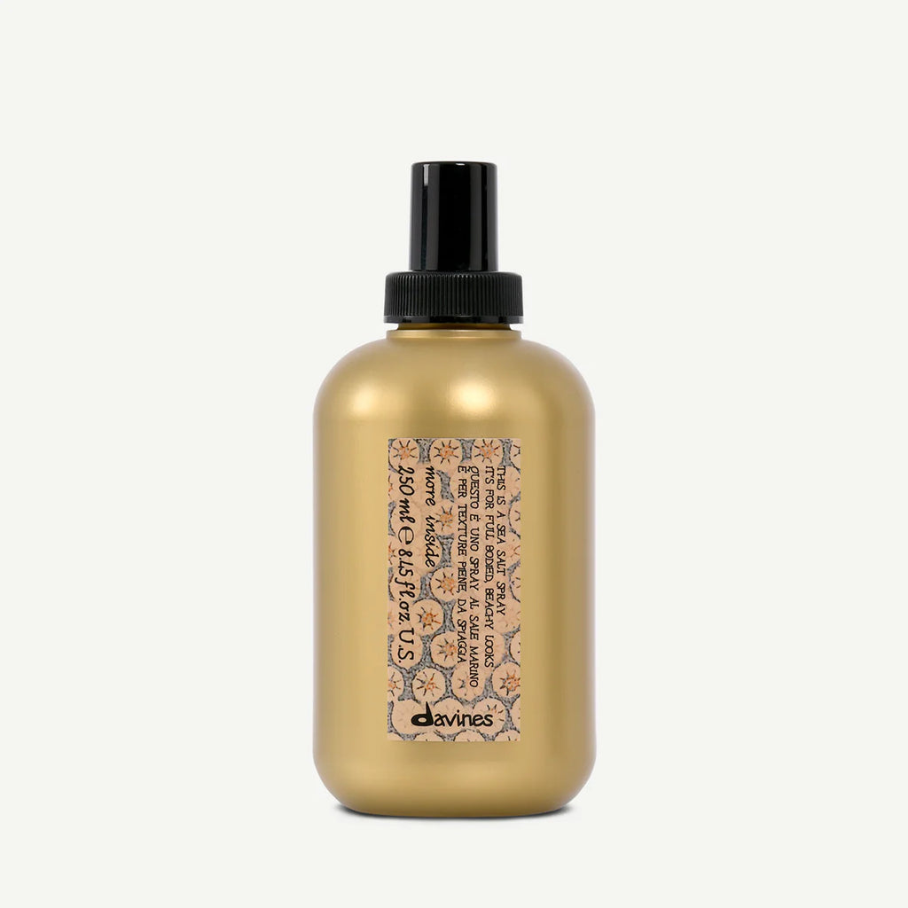 Flaska med This is a Sea Salt Spray från Davines, en stylingprodukt i en guldfärgad behållare med svart spraylock för volym och textur i håret.
