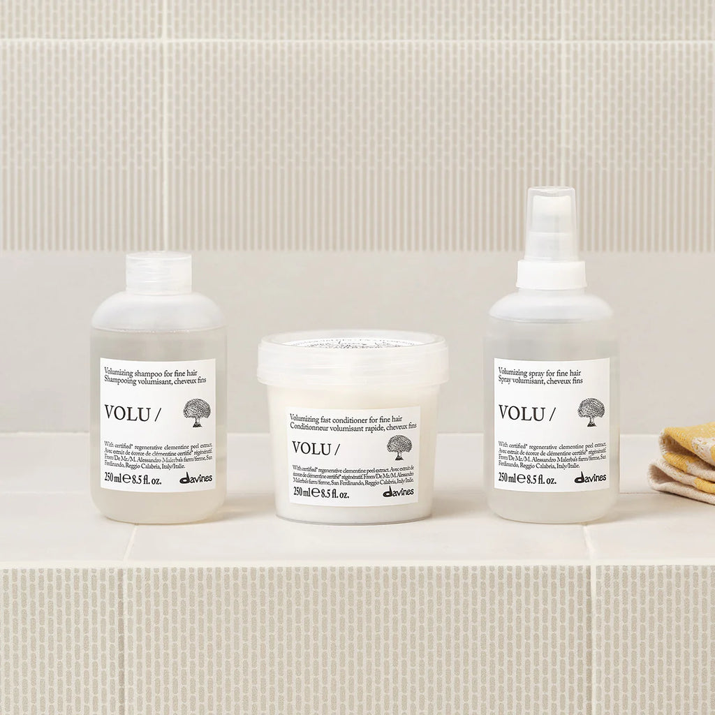 Volu Volumizing Fast Conditioner i en vit burk tillsammans med matchande miljövänliga hårvårdsprodukter från Davines på beige kakelbakgrund.