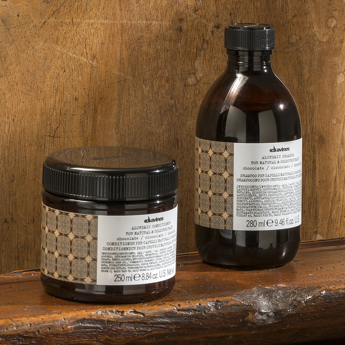 Alchemic Conditioner Chocolate balsam i brun behållare med svart lock, placerad på träyta bredvid matchande produktflaska, naturlig och miljövänlig hårvårdsprodukt.