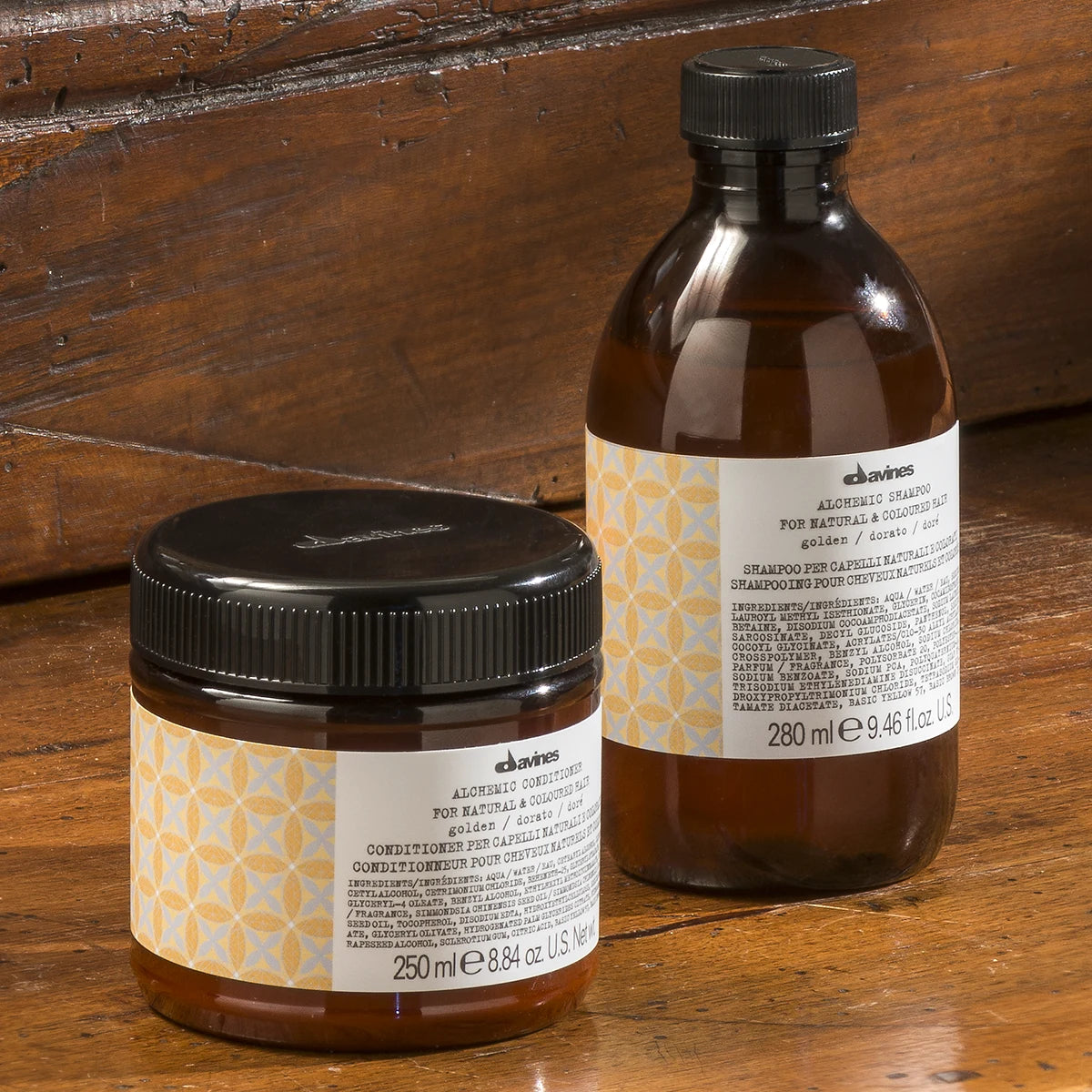 Alchemic Conditioner Golden balsam i burk bredvid matchande schampoflaska på träbord, miljövänliga hårvårdsprodukter för färgat hår.