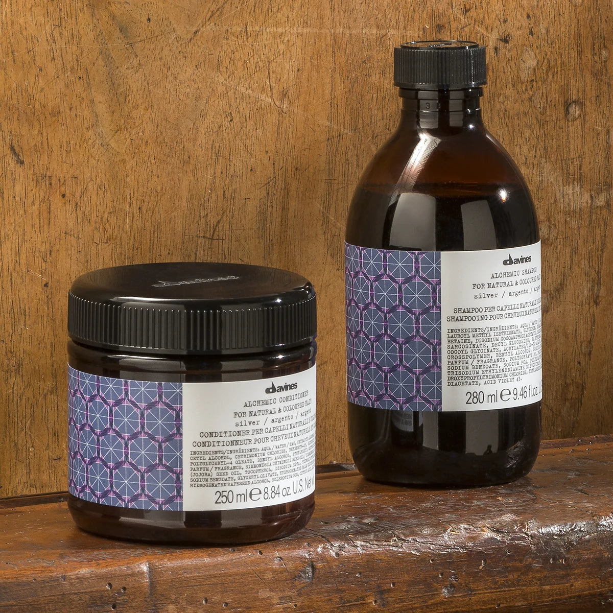 Alchemic Shampoo Silver i en brun flaska med text och mönstrad etikett bredvid en burk med balsam, placerade på träyta.