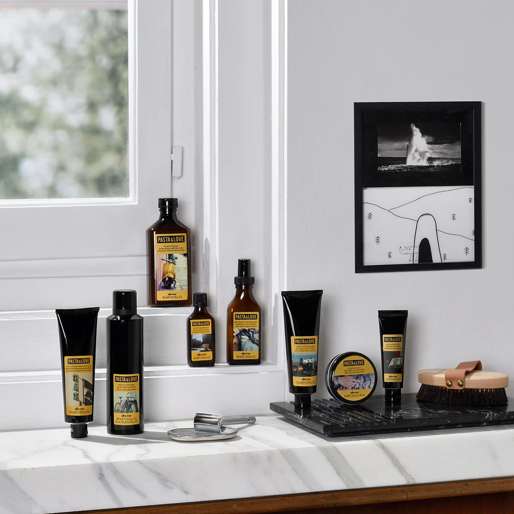 Pasta & Love Hair Beard & Body Wash blandat med andra hårvårdsprodukter på marmorbänkskiva i ett ljust rum med fönster och minimalistisk väggdekoration.