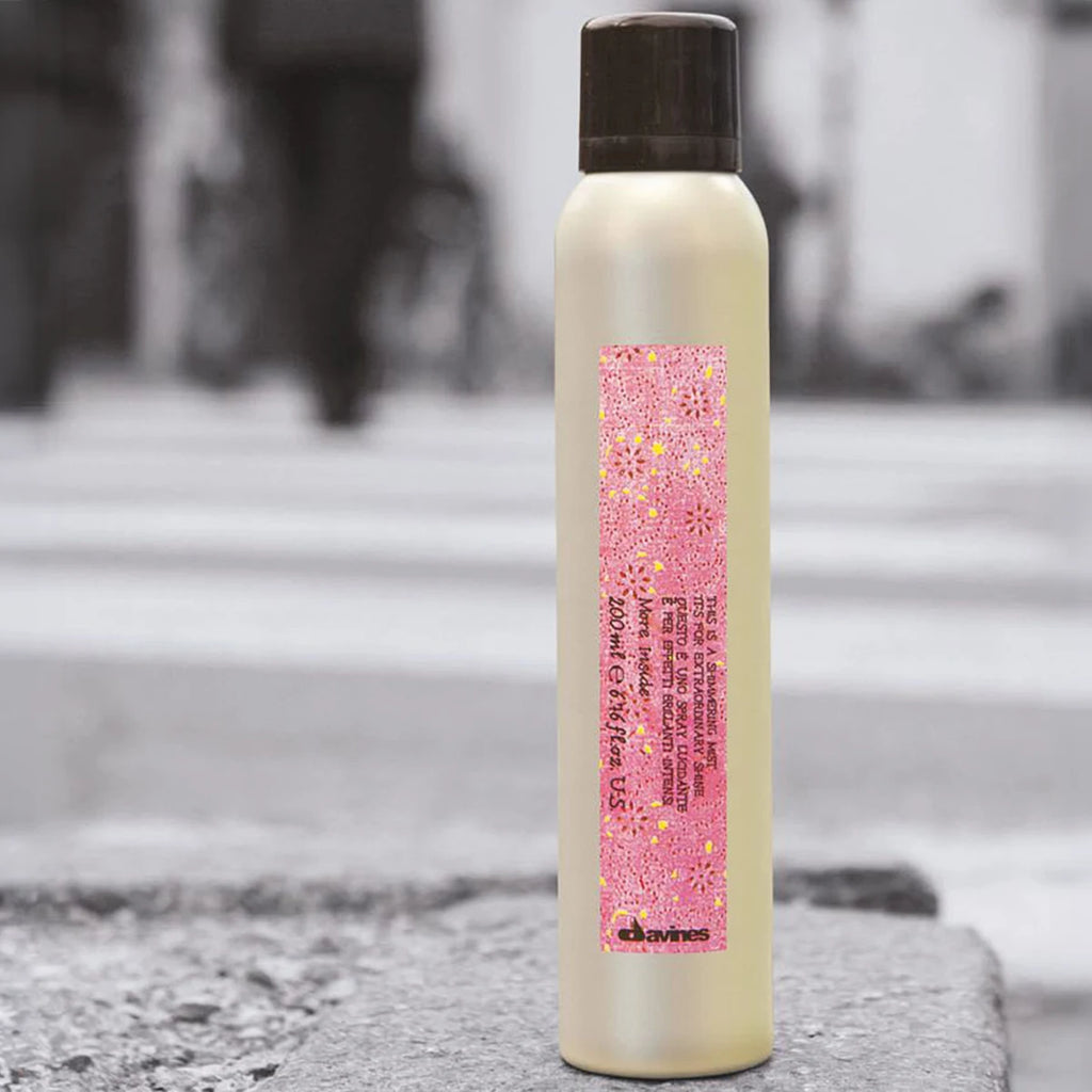 En elegant flaska med hårspray från Davines med rosa etikett och text, This is a Shimmering Mist för glans och lätt styling av håret.