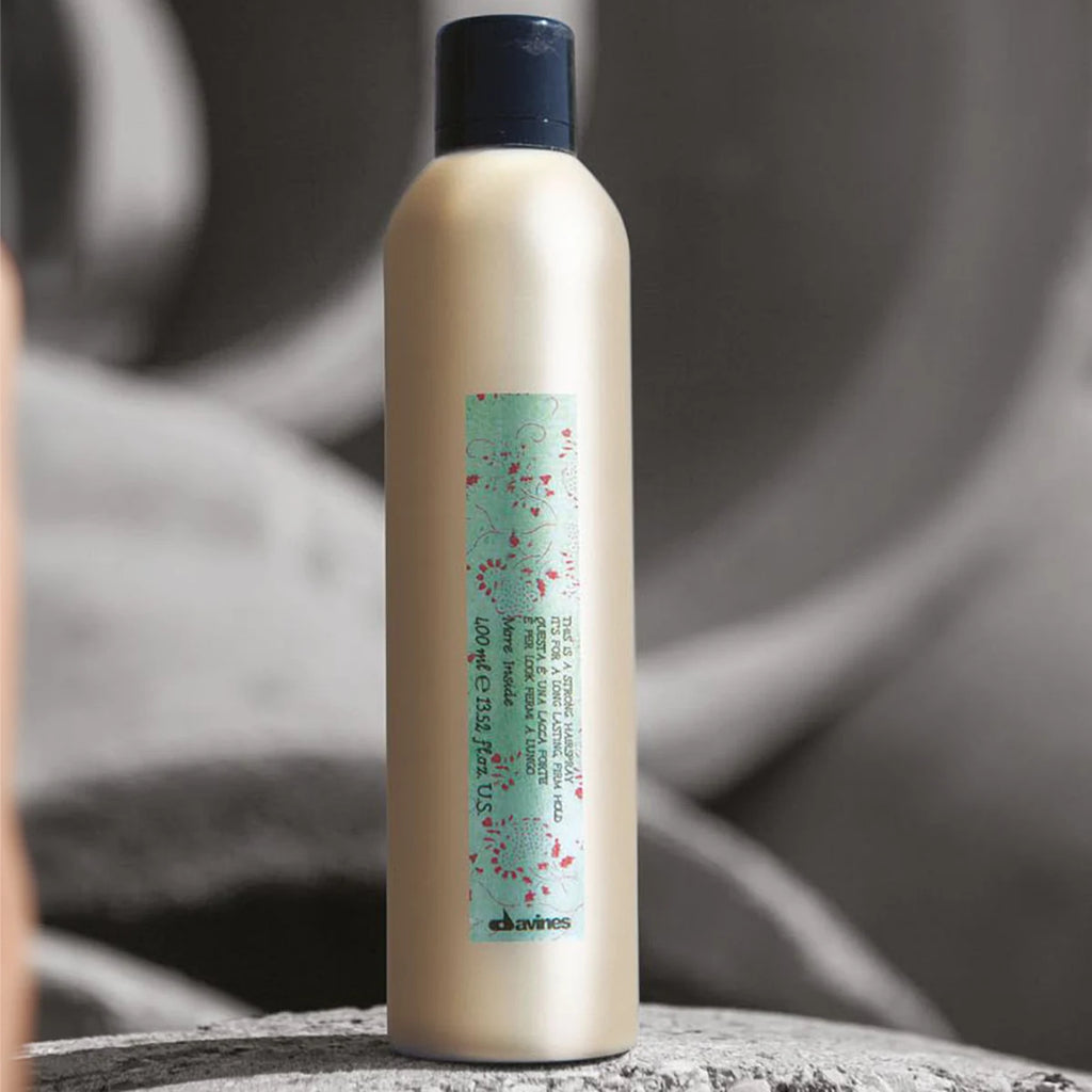 This is a Strong Hair Spray i en stilren beige flaska med svart lock, perfekt för styling och hållbar fixering av håret med miljövänliga hårvårdsprodukter.